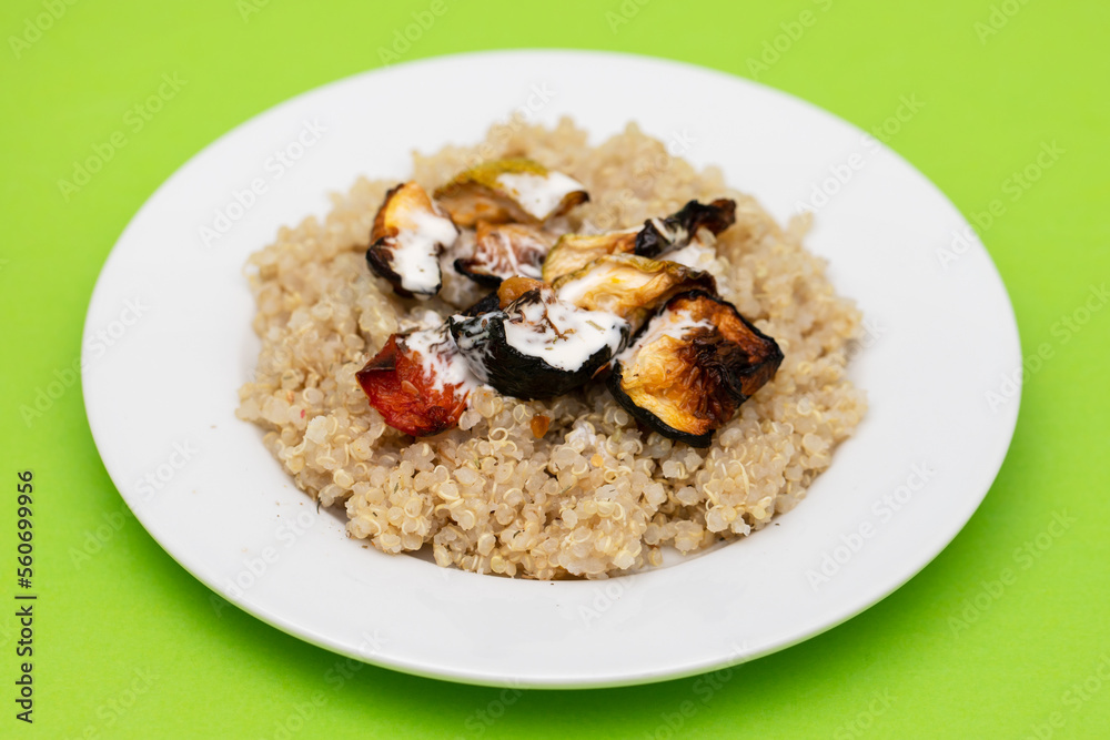 Cooked quinoa with vegetables and sauce on white plate