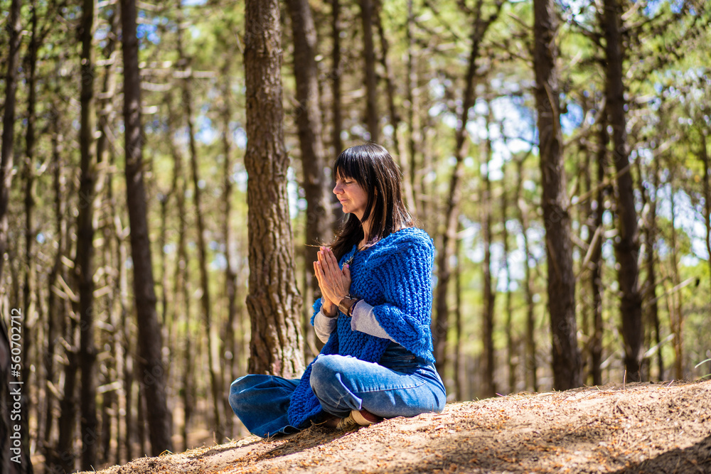Side view of a woman clasping hands in the woods. Namaste pose. Side view of a woman clasping hands in the woods. Namaste pose.