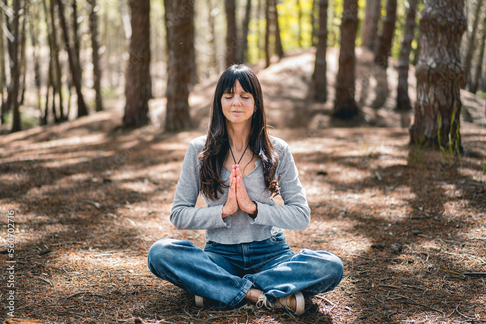 Front view of a woman clasping hands in the woods. Namaste pose. Front view of a woman clasping hands in the woods. Namaste pose.