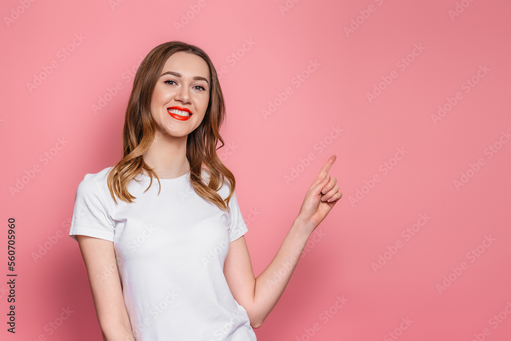 girl with in a white t-shirt smiles and points her finger at copy space girl with in a white t-shirt smiles and points her finger at copy space
