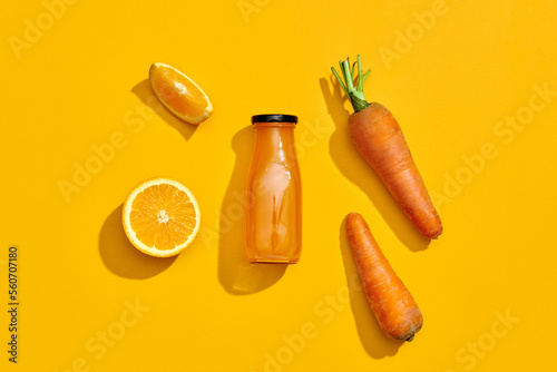 Vegetable smoothie or juice with carrot, oranges on yellow