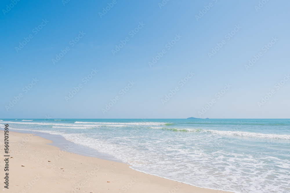 Emerald sea wave and white boiling foam surf on the tropical sandy beach with clear cloud and blue bright sky background in summer