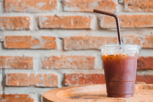 Wallpaper Mural Side view of iced dark cold brew americano coffee on the plastic up and brown plastic straw on the wooden table with orange brick block background and copy space Torontodigital.ca