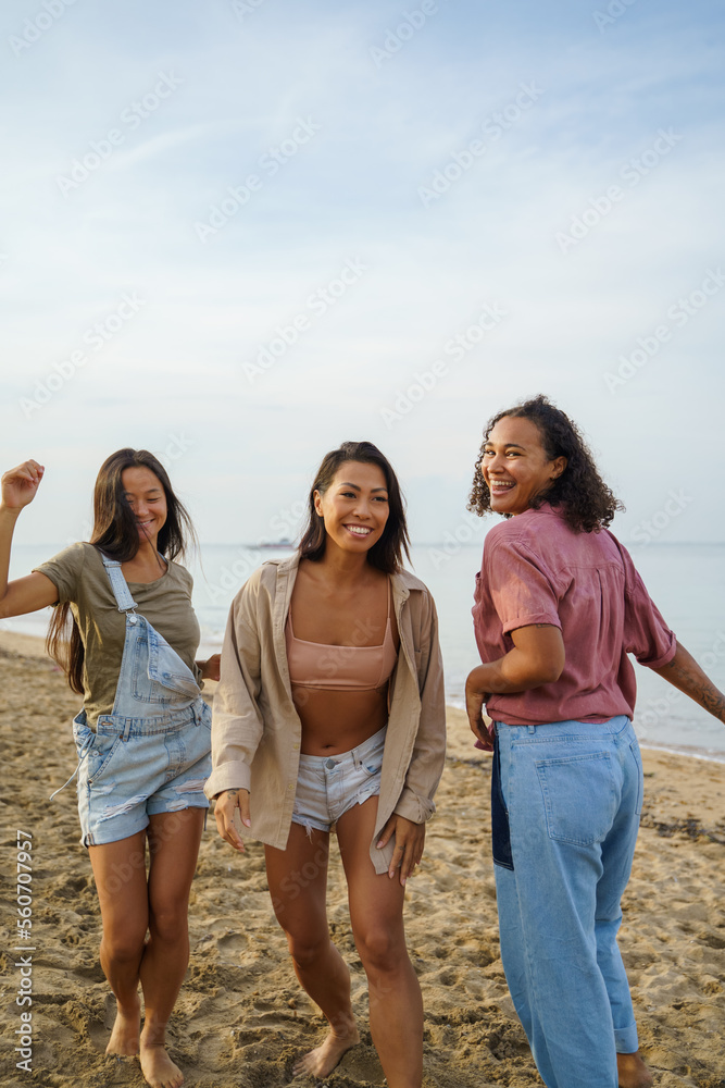 Cheerful friends dancing on sea shore at beach Cheerful friends dancing on sea shore at beach