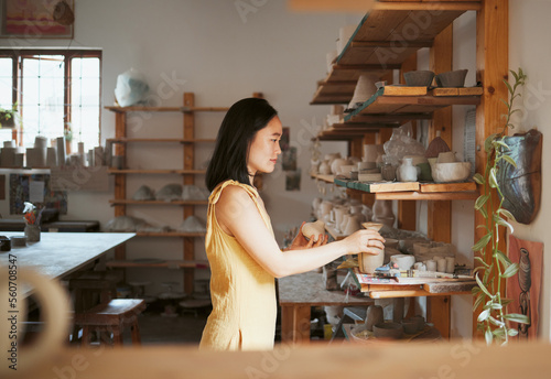 Woman, ceramic product and shelf in workshop, creative studio and manufacturing startup. Female small business owner, pottery designer and artist working with sculpture, creativity and craft process