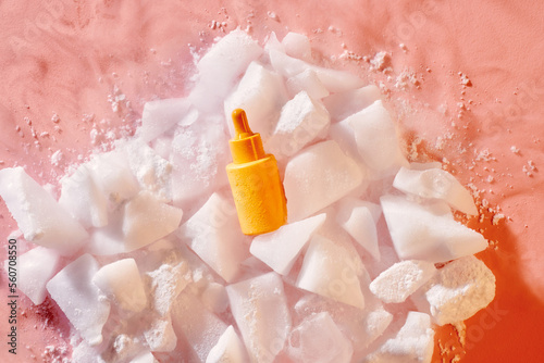 Close-up serum in glass bottle with water drops in ice background  photo