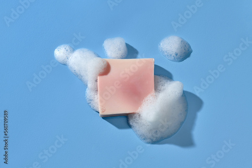 Soap bar and foam on blue background, top view. Mockup for design photo