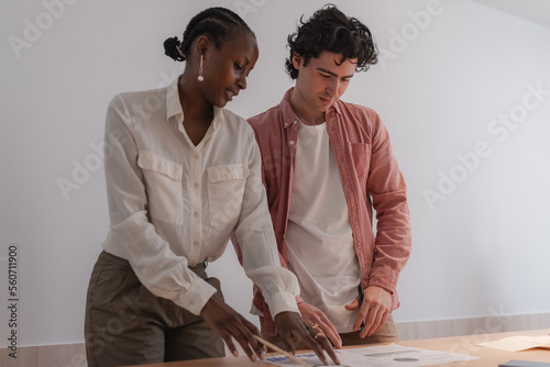 Multiracial colleagues analyzing papers on table