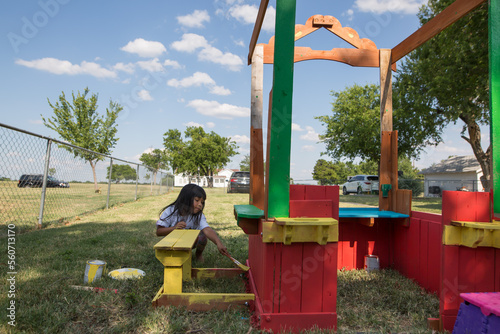 Little girl painting a colorful clubhouse in the backyard photo