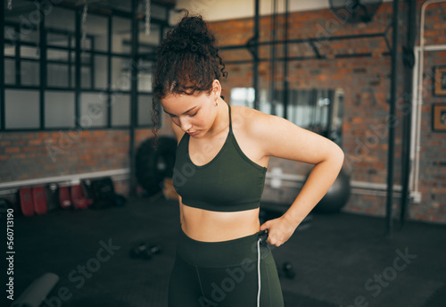 Fitness, exercise and woman at gym to check body progess after training for health, balance and wellness. A young sports female or athlete strong and healthy while on diet and active to lose weight photo