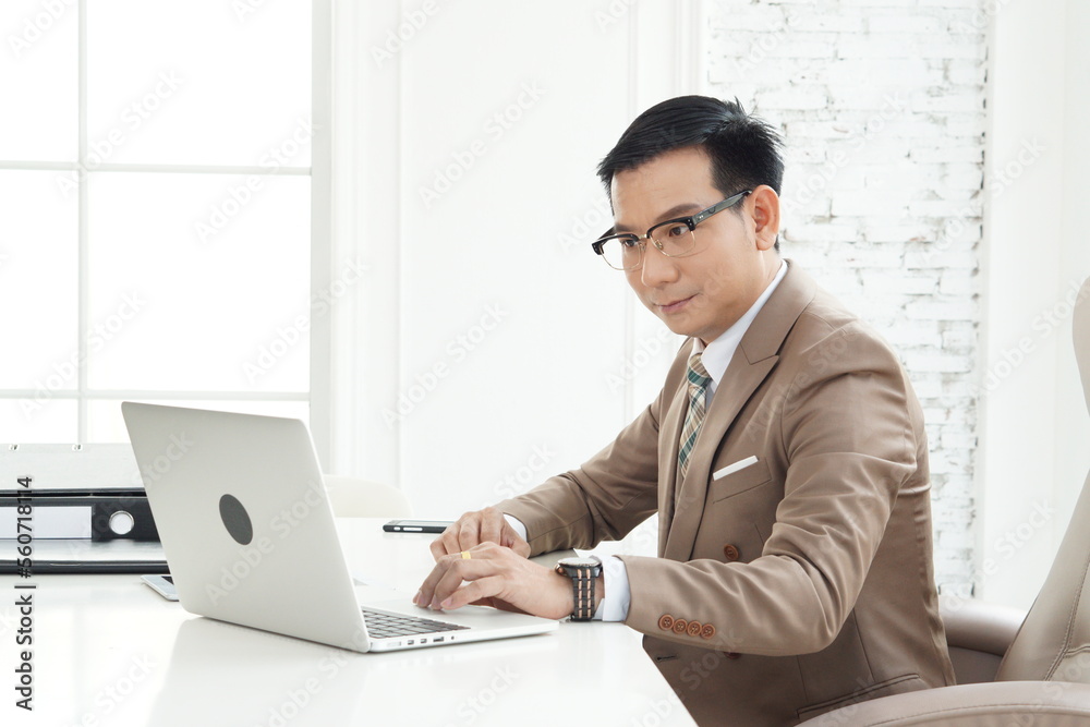 Asian handsome senior successful businessman using computer laptop to researching and working. sit in the private office Asian handsome senior successful businessman using computer laptop to researching and working. sit in the private office