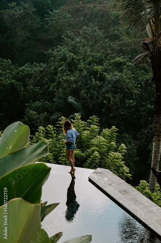 Young travelling girl walking on the edge of an infinity pool in a luxurious home in Ubud, Bali, Indonesia.  © Michal