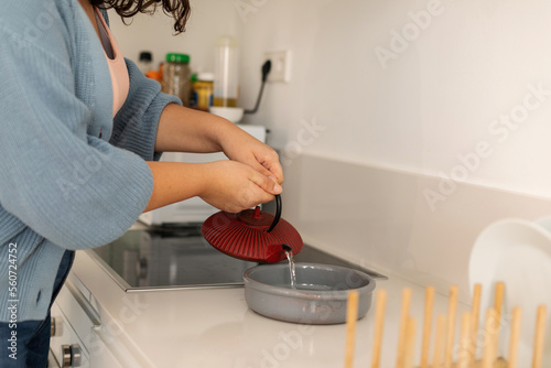 Female serving hot water cooking at kitchen