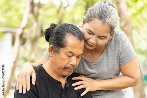 Old senior woman hugging, taking care of her husband suffering from Alzheimer disease