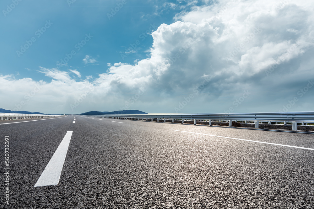 Fototapeta premium Asphalt road and river with mountain nature landscape under blue sky