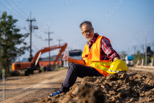 Male engineer takes a break to drink water to relax in the sweltering midday heat.