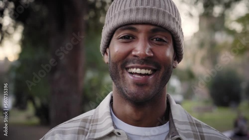 Close up portrait of Handsome smiling young African man with knit hat looking at camera with positive expression. Happy latin guy outdoors. Cheerful real people. photo