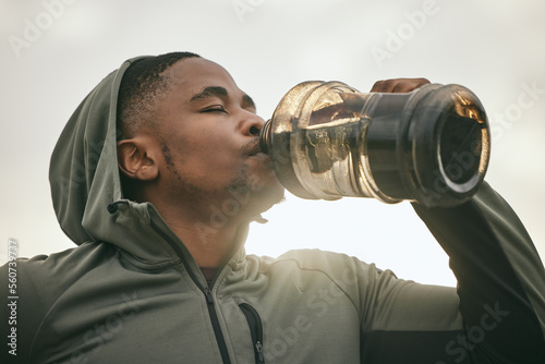 Fitness, health or black man drinking water after training, exercise or workout for body hydration. Thirsty runner, bottle or tired sports athlete relaxing with goals or motivation resting in Chicago