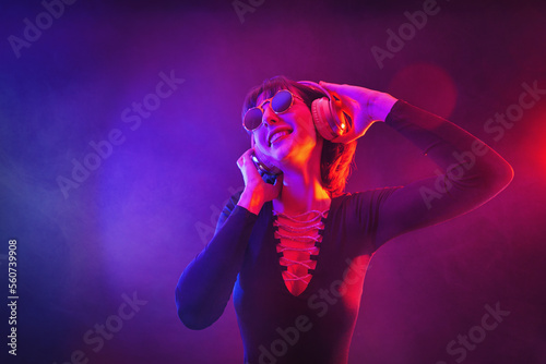 Portrait of fashion young girl in sunglasses and headphones in red and blue neon light in the studio