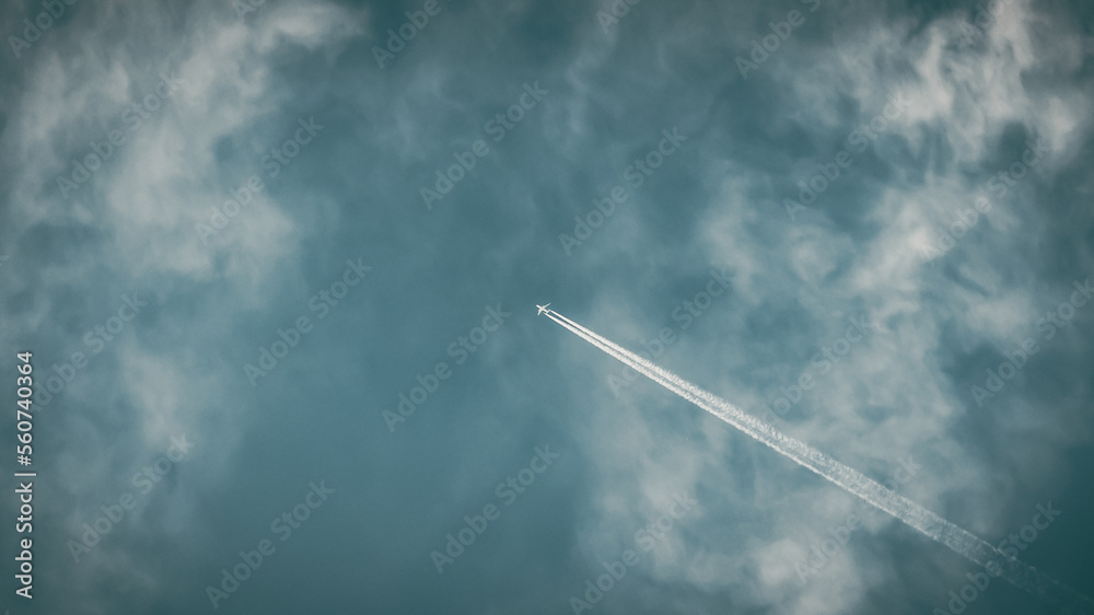 Plane flying high in the sky leaving behind a long contrail. Stunning ...