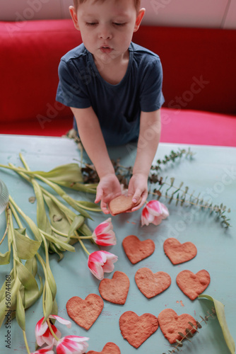 Baby boy holding heart shaped cookies on the table.Valentines, mothers, womens day, wedding or birthday flat lay concept. Top view.