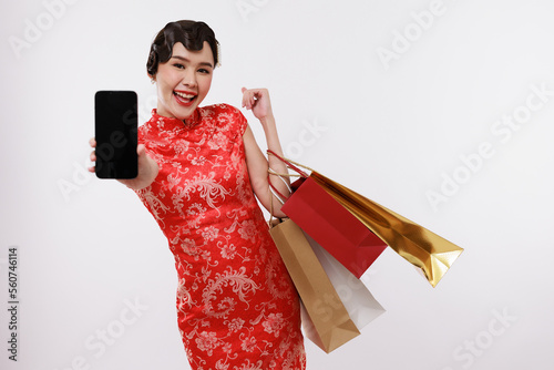 Smiling young beautiful woman holding a phone and shopping bag in traditional dress on isolated white background.