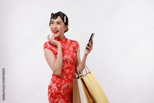 Smiling young beautiful woman holding a phone and shopping bag in traditional dress on isolated white background.