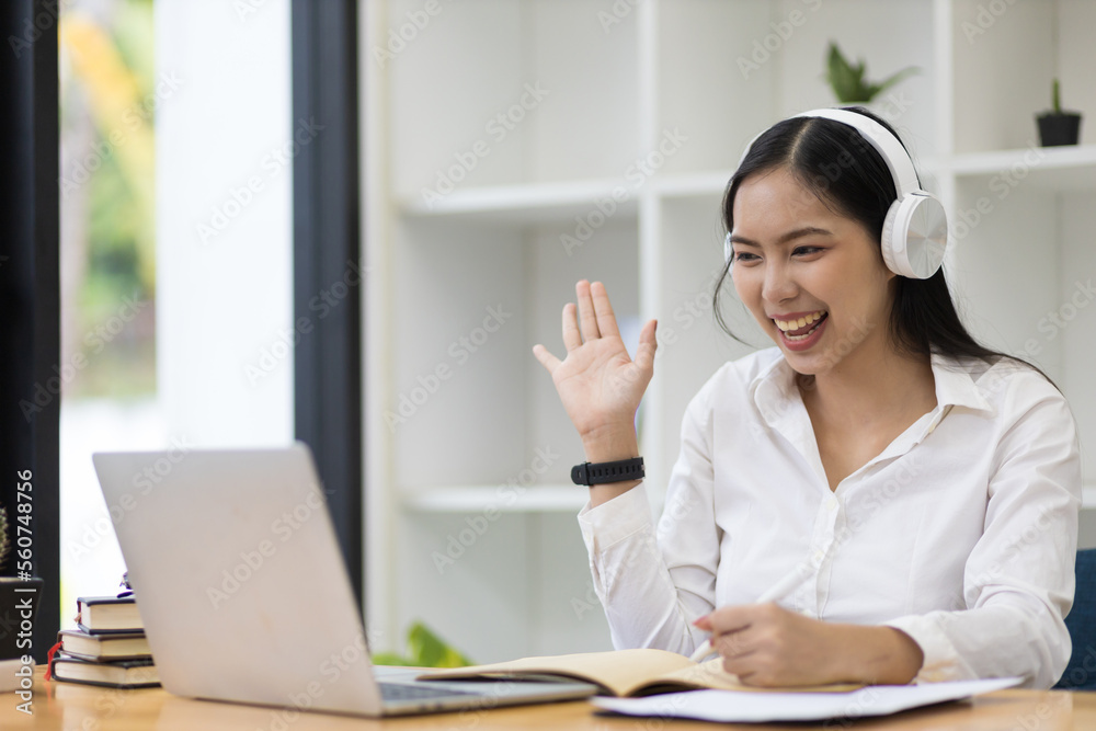 Asian woman working with laptop while having online conference at home office. Asian woman working with laptop while having online conference at home office.