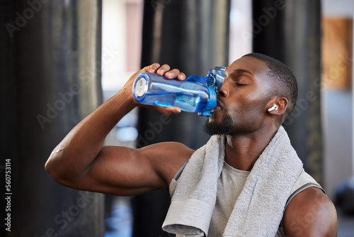 Drinking water, fitness and gym with a black man athlete taking a break from his exercise or workout routine. Training, health and wellness with a sporty male having a drink for hydration or recovery photo