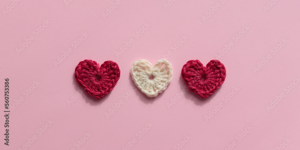 Crocheted amigurumi pink, red and white hearts on a pink background. Valentine's pattern banner