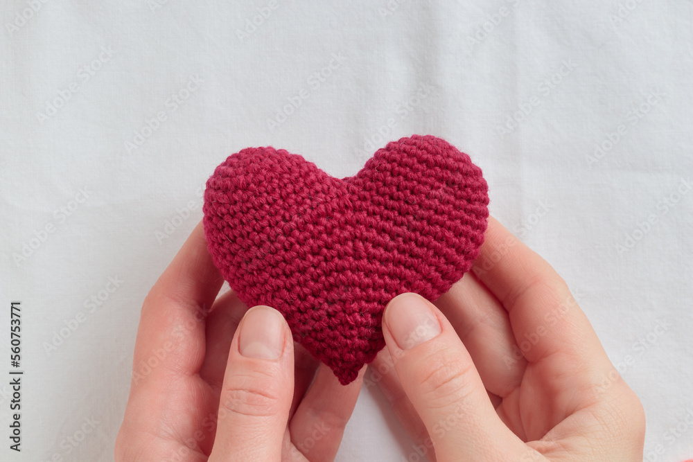 Crocheted amigurumi purple heart in a woman's hands. Valentine's day banner