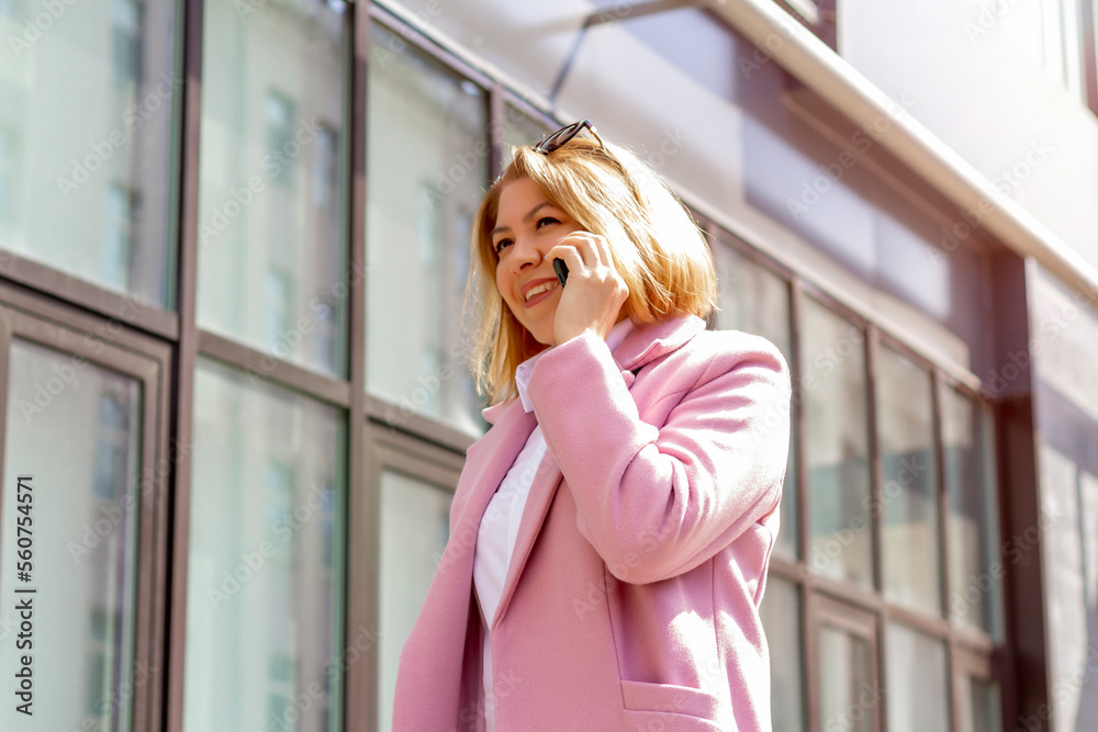 A woman with short brown hair walks around the city and talks on the phone in the spring. fashion style trend, black friday sale. A woman with short brown hair walks around the city and talks on the phone in the spring. fashion style trend, black friday sale.