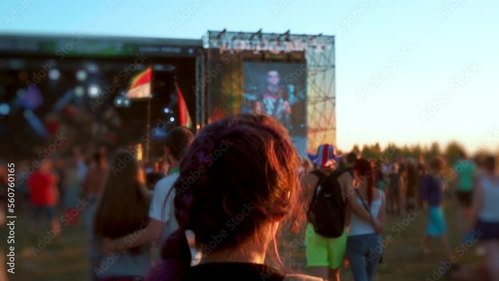 Woman running to stage. Diverse group of fans dancing at openair live rock concert. Asian woman slam at music festival outdoor. Rebellious young anarchist people listening to alternative punk songs