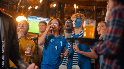 Group of Multicultural Friends Watching a Live Soccer Match in a Sports Bar. Excited Fans with Painted Faces Cheering. Young People Celebrating When Team Scores a Goal and Wins the Football World Cup.