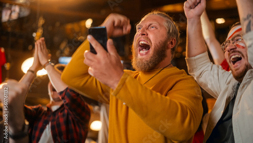 Fototapeta Naklejka Na Ścianę i Meble -  Excited Masculine Man Holding a Smartphone, Feeling Nervous About the Sports Bet He Put on a Favorite Soccer Team. Ecstatic When Football Team Scores a Goal and He Wins a High Stakes Casino Prize.