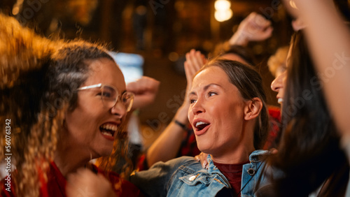 Three Female Friends Watching a Live Soccer Match on TV in a Sports Bar. Happy Girls Cheering and Shouting. Young Fans Celebrating When Team Scores a Goal and Wins the Football World Cup.