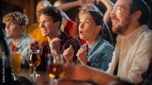 Excited Beautiful Female Sitting at a Bar Stand with Group of Friends, Cheering for a Soccer Team Playing in Tournament. Supportive Fans Applauding, Raising and Shouting in a Sports Pub. © Gorodenkoff