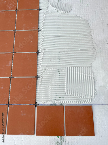 worker spreads the cement glue before applying the ceramic tiles
 photo