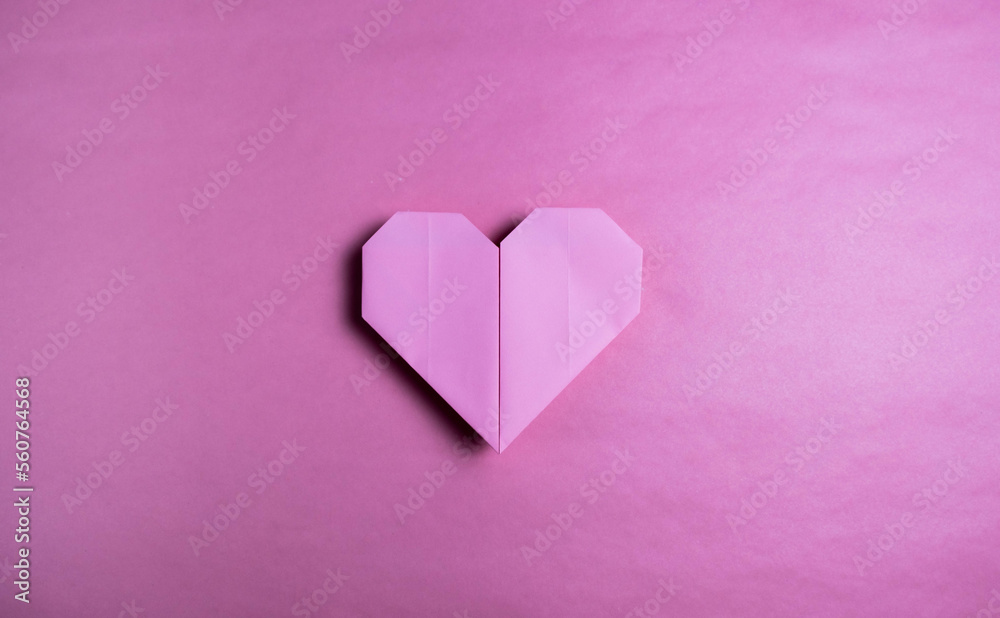Pink heart made in origami on a background of the same color. Valentine's Gift Concept, February 14. Handmade