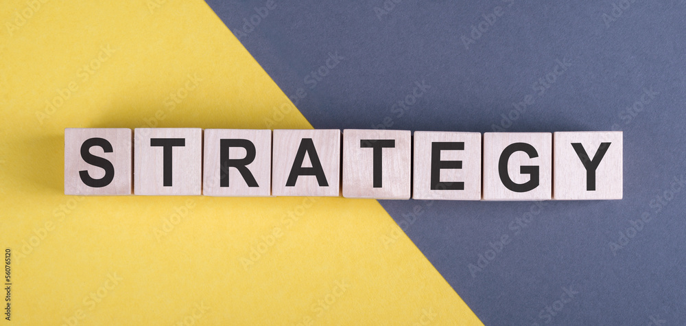 Obraz premium STRATEGY word written on wood blocks on yellow and gray background