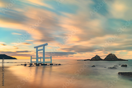 Long exposure art photography of a sunset seascape depicting the Itoshima Beach of Fukuoka famous for its white Shinto torii gate in front of the Couple Rocks called Sakurai Futamigaura's Meoto Iwa.