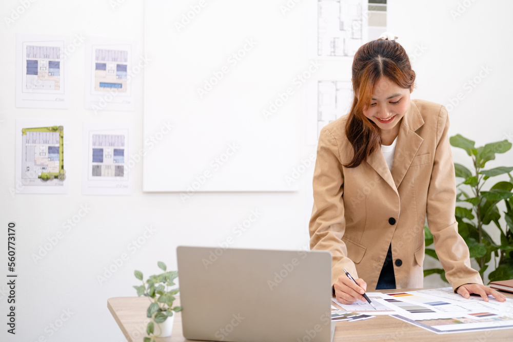 Professional interior designer working in the office, Portrait of young asian female architect working on business of Real estateproject , sketching on a house plan choosing swatches and material.. Professional interior designer working in the office, Portrait of young asian female architect working on business of Real estateproject , sketching on a house plan choosing swatches and material..