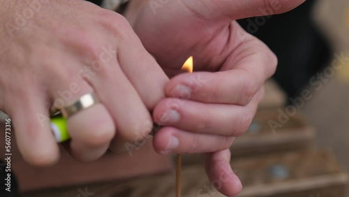 close-up of male hands lighting an incense stick with a lighter