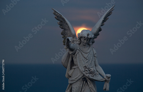 tombstone statue with red moon rising between wings