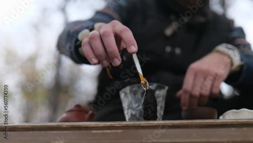 tea master pours tea on a tea figurine. outdoors tea ceremony