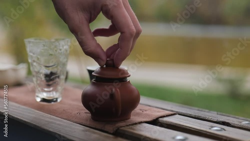 close-up, male hand closes the lid of a clay teapot. outdoors tea ceremony