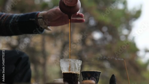 tea master pours strong brewed pu-erh tea from a clay teapot into a glass vessel