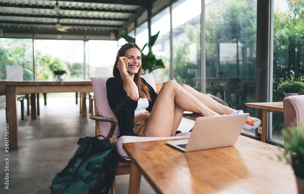 Cheerful woman speaking on smartphone in cafe