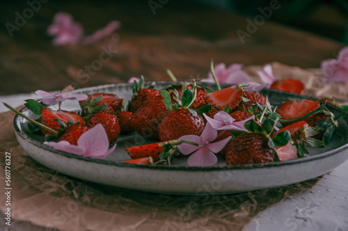 New harvest, plate with ripe red sweet strawberry on farmer fields and green leaves of strawberry plants close up