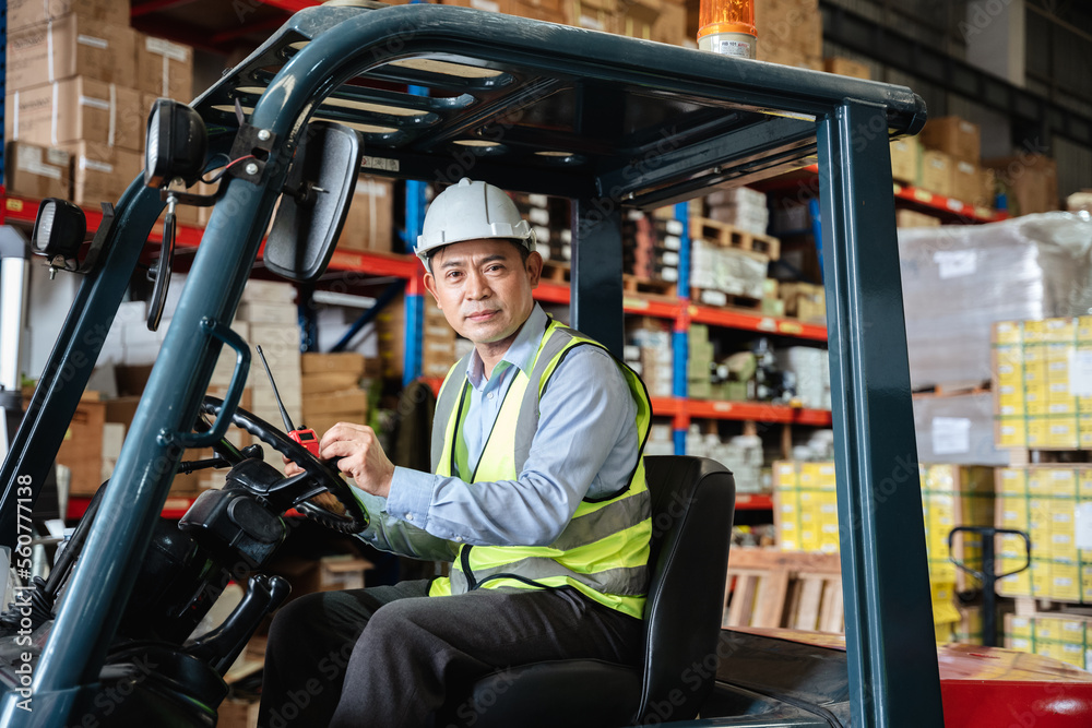 Fototapeta premium A warehouse worker forklift operator moves packages around with a manufacturing facility.